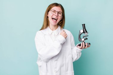 Kızıl saçlı güzel bir kadın kendini mutlu hissediyor ve bir meydan okumayla yüzleşiyor ya da kutluyor. Mikroskop konseptine sahip bilim adamı