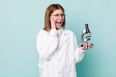 Kızıl saçlı güzel kadın mutlu, heyecanlı ve şaşırmış hissediyor. Mikroskop konseptine sahip bilim adamı