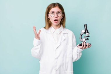 Kızıl saçlı güzel kadın çok şaşırmış ve şok olmuş hissediyor. Mikroskop konseptine sahip bilim adamı