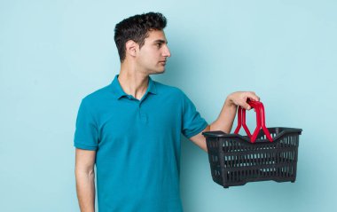 Profil görünümlü yakışıklı İspanyol adam düşünüyor, hayal ediyor ya da hayal kuruyor. Alışveriş sepeti konsepti