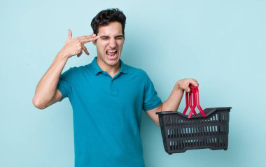 Yakışıklı İspanyol adam mutsuz ve stresli görünüyor, intihar jesti silah işareti yapıyor. Alışveriş sepeti konsepti