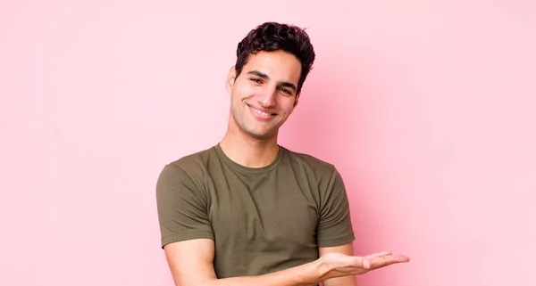 ハンサムなヒスパニック系の男は陽気に笑って幸せと手の手のひらでコピースペースで概念を示しています — ストック写真