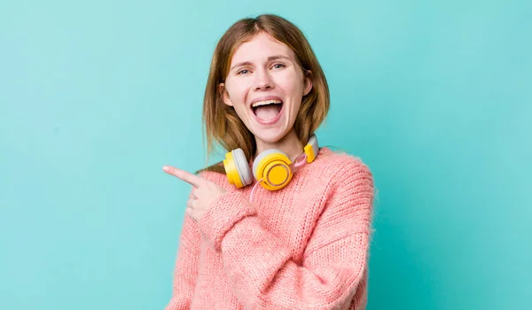 Red Head Pretty Woman Looking Excited Surprised Pointing Side Headphones — Stockfoto