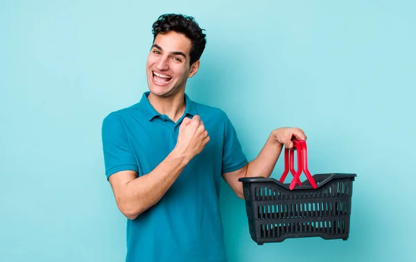 ハンサムなヒスパニック系の男は幸せと挑戦やお祝いに直面しています ショッピングバスケットのコンセプト — ストック写真