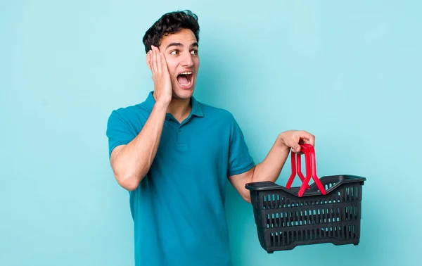 ハンサムなヒスパニック系の男は 興奮し 驚いて幸せを感じる ショッピングバスケットのコンセプト — ストック写真
