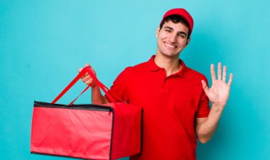 Yakışıklı İspanyol adam mutlu bir şekilde gülümsüyor, el sallıyor, seni selamlıyor ve selamlıyor. Pizza dağıtımı kavramı