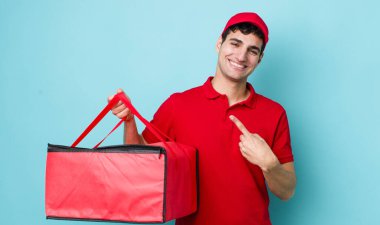 Yakışıklı İspanyol adam neşeyle gülümsüyor, mutlu hissediyor ve bir tarafı işaret ediyor. Pizza dağıtımı kavramı