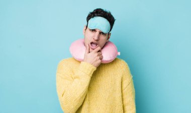 Ağzı ve gözleri açık, eli çenesinde yakışıklı İspanyol bir adam. uçuş yolcu kavramı