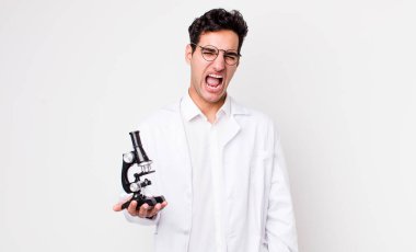 Yakışıklı İspanyol adam agresif bir şekilde bağırıyor, mikroskop konsepti olan kızgın bir bilim adamı gibi görünüyor.
