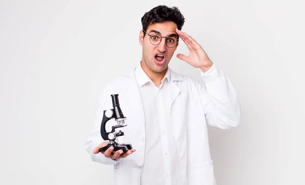 Przystojny Latynos Mężczyzna Wygląda Szczęśliwy Zdumiony Zaskoczony Naukowiec Mikroskopem Pomysł — Zdjęcie stockowe