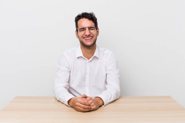 İspanyol yakışıklı bir adam komik bir şakaya yüksek sesle gülüyor. iş adamı ve masa başı konsepti