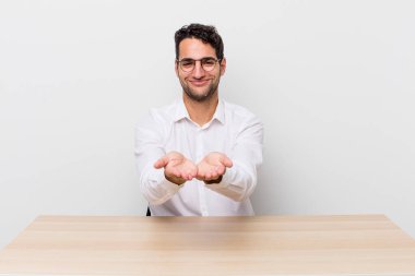 İspanyol yakışıklı adam mutlu bir şekilde gülümsüyor ve bir konsept sunuyor. iş adamı ve masa başı konsepti