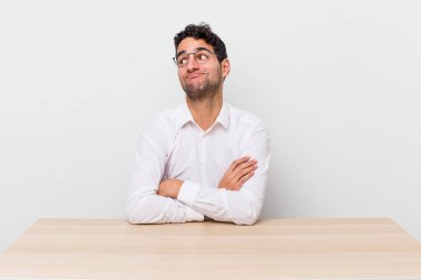 İspanyol yakışıklı adam omuz silkiyor, kafası karışık ve kararsız. iş adamı ve masa başı konsepti