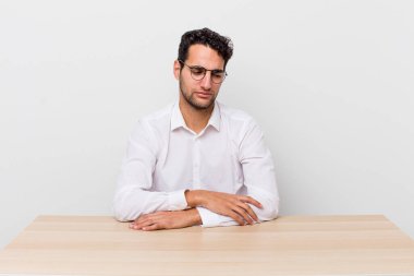 Hispanik yakışıklı adam üzgün, üzgün ya da kızgın hissediyor ve yana bakıyor. iş adamı ve masa başı konsepti