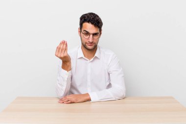 İspanyol yakışıklı adam kapiş ya da para hareketi yapıyor, sana ödemeni söylüyor. iş adamı ve masa başı konsepti