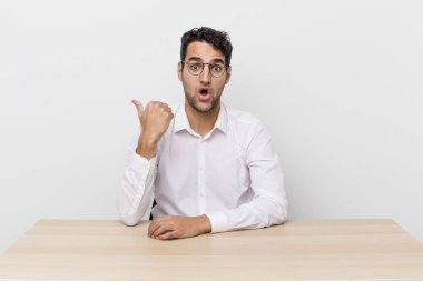 İspanyol yakışıklı adam, inançsızlıktan şaşkın şaşkın bakıyor. iş adamı ve masa başı konsepti