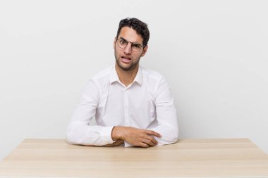 İspanyol yakışıklı adam şaşkın ve şaşkın hissediyor. iş adamı ve masa başı konsepti