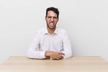 İspanyol yakışıklı adam iğreniyor, sinirleniyor ve dili dışarı çıkıyor. iş adamı ve masa başı konsepti