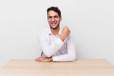 İspanyol yakışıklı adam kendini mutlu hissediyor ve bir meydan okumayla yüzleşiyor ya da kutluyor. iş adamı ve masa başı konsepti