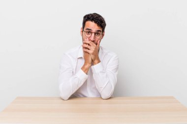 İspanyol yakışıklı adam şok olmuş bir şekilde ağzını kapatıyor. iş adamı ve masa başı konsepti