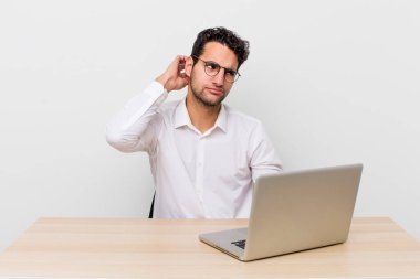 İspanyol yakışıklı adam mutlu bir şekilde gülümsüyor ve hayal kuruyor ya da şüphe ediyor. iş adamı ve masa başı konsepti