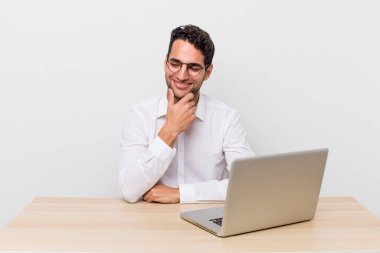 Mutlu, kendine güvenen, elleri çenesinde gülümseyen İspanyol yakışıklı bir adam. iş adamı ve masa başı konsepti