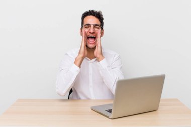 İspanyol yakışıklı adam kendini mutlu hissediyor, elleri ağızının yanında bağırıyor. iş adamı ve masa başı konsepti