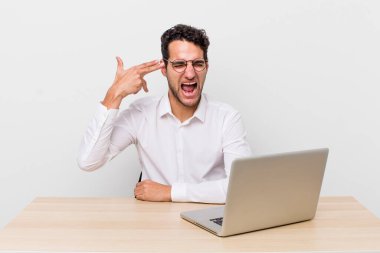 İspanyol yakışıklı adam mutsuz ve stresli görünüyor, intihar jesti silah işareti yapıyor. iş adamı ve masa başı konsepti