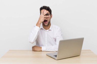 İspanyol yakışıklı adam şok olmuş, korkmuş ya da korkmuş görünüyor. Yüzü elle kapatılmış. iş adamı ve masa başı konsepti