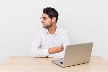 Profil görünümlü İspanyol yakışıklı adam hayal mi kuruyor, hayal mi kuruyor, hayal mi kuruyor? iş adamı ve masa başı konsepti