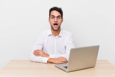 İspanyol yakışıklı adam çok şaşırmış ya da şaşkın görünüyor. iş adamı ve masa başı konsepti