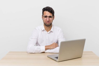 Hispanik yakışıklı adam üzgün ve mızmız, mutsuz bir bakışla ağlıyor. iş adamı ve masa başı konsepti