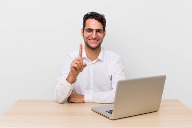 Hispanik yakışıklı adam gururla gülümsüyor ve kendinden emin bir numara oluyor. iş adamı ve masa başı konsepti