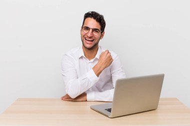 İspanyol yakışıklı adam kendini mutlu hissediyor ve bir meydan okumayla yüzleşiyor ya da kutluyor. iş adamı ve masa başı konsepti