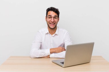 İspanyol yakışıklı adam mutlu ve hoş bir şekilde şaşırmış görünüyor. iş adamı ve masa başı konsepti