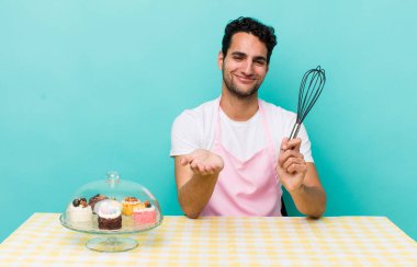 İspanyol yakışıklı adam mutlu bir şekilde gülümsüyor ve bir konsept sunuyor. Ev yapımı pastalar.