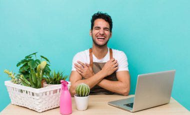 İspanyol yakışıklı bir adam komik bir şakaya yüksek sesle gülüyor. bahçe ve bitki konsepti