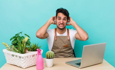 İspanyol yakışıklı adam kendini stresli, endişeli ya da korkmuş hissediyor, elleri başının üstünde. bahçe ve bitki konsepti