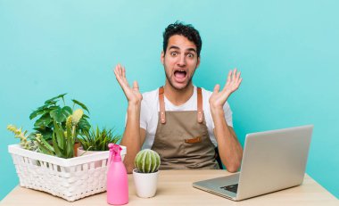 İspanyol yakışıklı adam kendini mutlu hissediyor ve inanılmaz bir şeye hayret ediyor. bahçe ve bitki konsepti