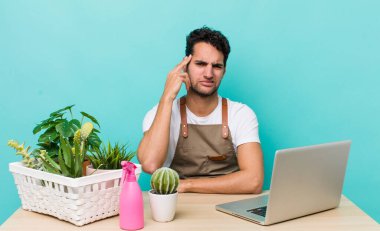 İspanyol yakışıklı adam kafası karışık ve şaşkın hissediyor, senin deli olduğunu gösteriyor. bahçe ve bitki konsepti