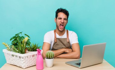 İspanyol yakışıklı adam agresif bir şekilde bağırıyor, çok kızgın görünüyor. bahçe ve bitki konsepti