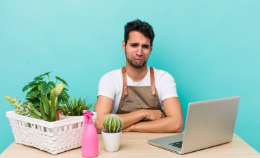 Hispanik yakışıklı adam üzgün ve mızmız, mutsuz bir bakışla ağlıyor. bahçe ve bitki konsepti