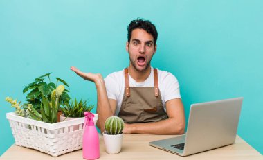 İspanyol yakışıklı adam şaşırmış ve şok olmuş görünüyor. Çenesi düşmüş ve elinde bir nesne var. bahçe ve bitki konsepti