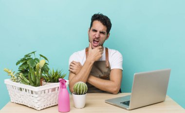Ağzı ve gözleri açık, eli çenesinde İspanyol yakışıklı bir adam. bahçe ve bitki konsepti
