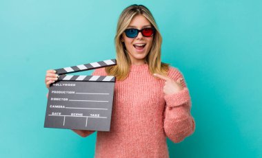 Güzel sarışın kadın mutlu hissediyor ve heyecanla kendini işaret ediyor. Sinema kavramı