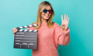 Güzel sarışın kadın gülümsüyor ve arkadaş canlısı görünüyor, dört numarayı gösteriyor. Sinema kavramı