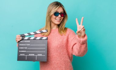 Güzel sarışın kadın gülümsüyor ve arkadaş canlısı görünüyor. İki numarayı gösteriyor. Sinema kavramı