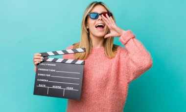 Güzel sarışın kadın kendini mutlu hissediyor, elleri ağzının kenarında bağırıyor. Sinema kavramı