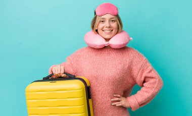 Güzel sarışın kadın mutlu bir şekilde gülümsüyor, eli kalçasında ve kendinden emin. uçuş yolcu kavramı