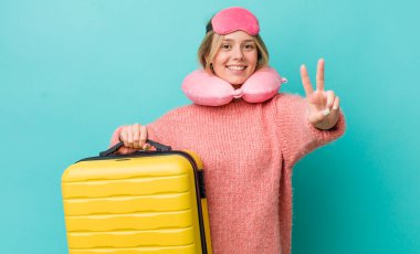 Güzel sarışın kadın gülümsüyor ve mutlu görünüyor, zafer ya da barış işareti yapıyor. uçuş yolcu kavramı